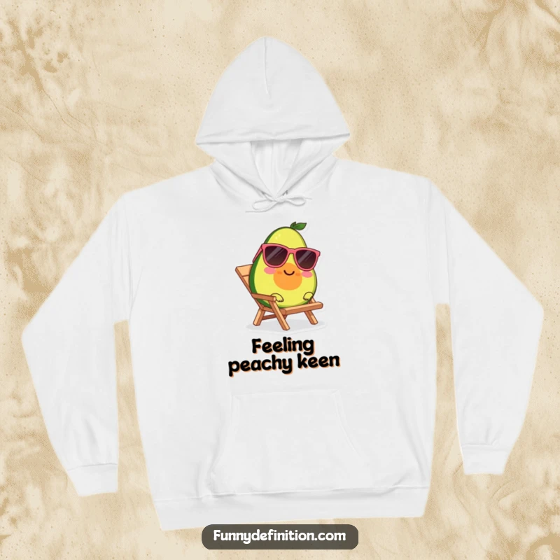 Funny, cozy hoodie featuring a smiling avocado wearing sunglasses, relaxing on a tiny beach chair.