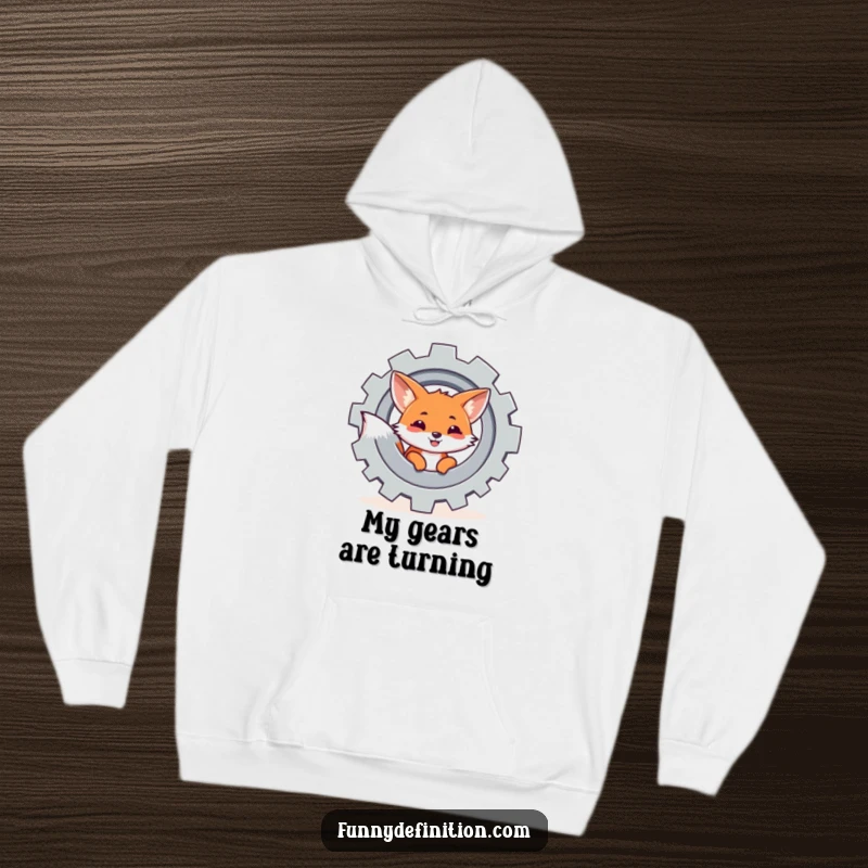 Funny hoodie featuring a mischievous fox observing a large, turning gear, symbolizing curiosity within a mechanical world.