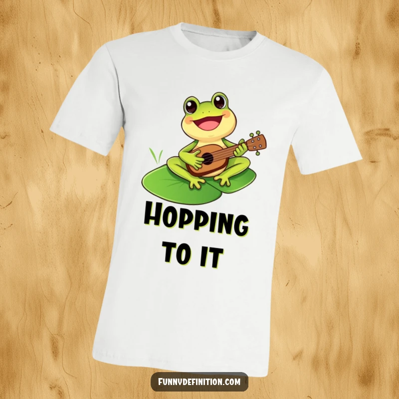 Funny cheerful frog joyfully playing a small ukulele atop a lily pad on a t-shirt.